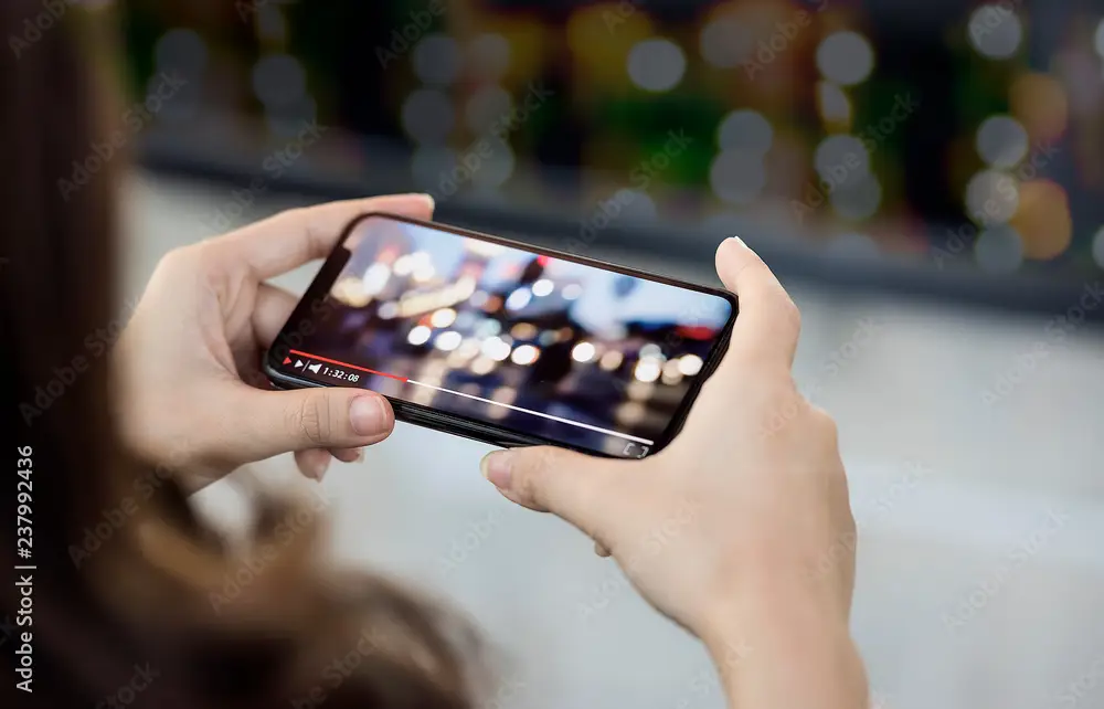 Pengalaman Menonton Anime Tangan memegang smartphone menonton anime