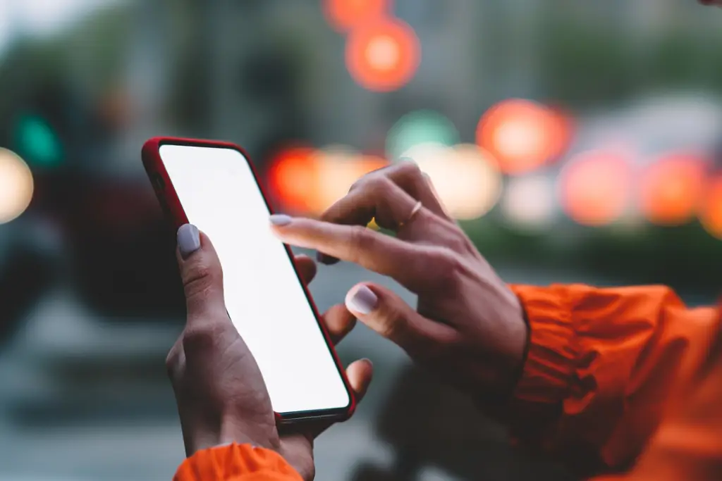 Menonton Anime Secara Legal Tangan memegang smartphone yang menampilkan aplikasi streaming anime